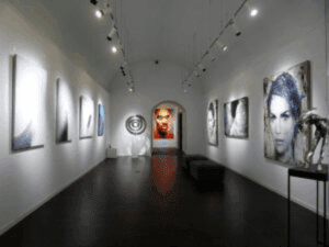  Modern art gallery interior featuring contemporary African paintings and portrait artworks under soft lighting, showcasing Ovico Gallery’s blend of culture, emotion, and visual storytelling. 