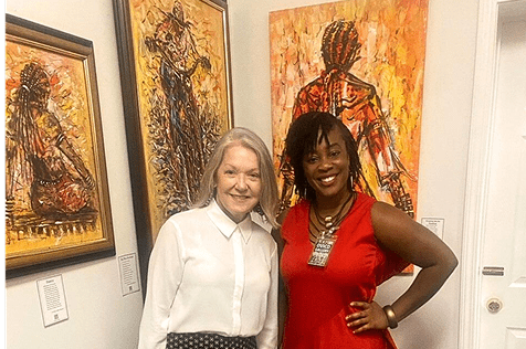 Visitors share a moment surrounded by vivid African paintings.