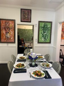 Table setting for a private luncheon inside a wall art gallery, featuring gourmet plated salads, elegant glassware, and vibrant paintings at Ovico Gallery in St. Augustine.
